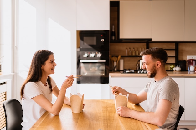 Hombre y mujer sonrientes almorzando juntos en casa.
