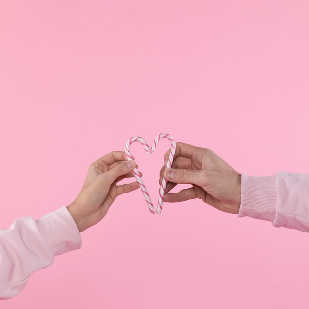 Hombre y mujer sosteniendo bastones de caramelo en forma de corazón