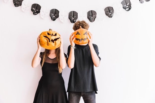 Foto gratuita hombre y mujer sosteniendo calabazas antes de caras