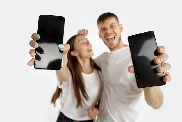 Hombre y mujer sosteniendo teléfonos inteligentes y mostrando pantallas.