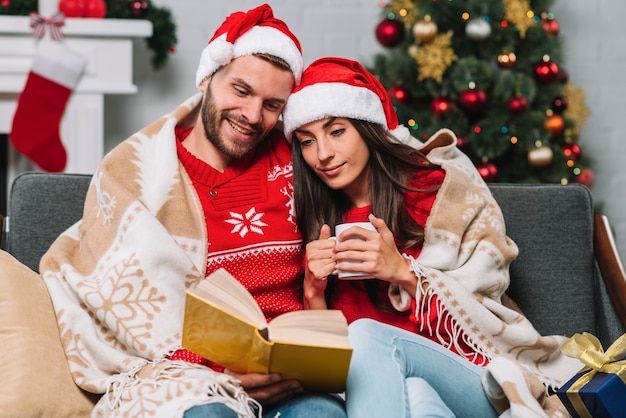 Hombre y mujer con taza leyendo libro