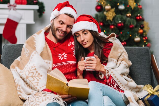 Hombre y mujer con taza leyendo libro