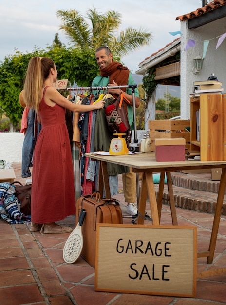 Hombre y mujer de tiro completo en una venta de garaje