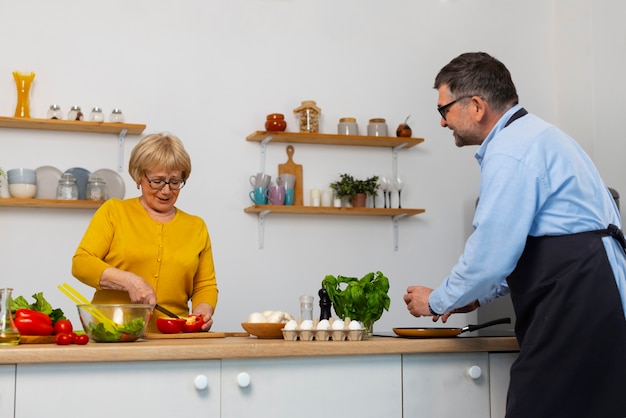 Hombre y mujer de tiro medio cocinando en la cocina