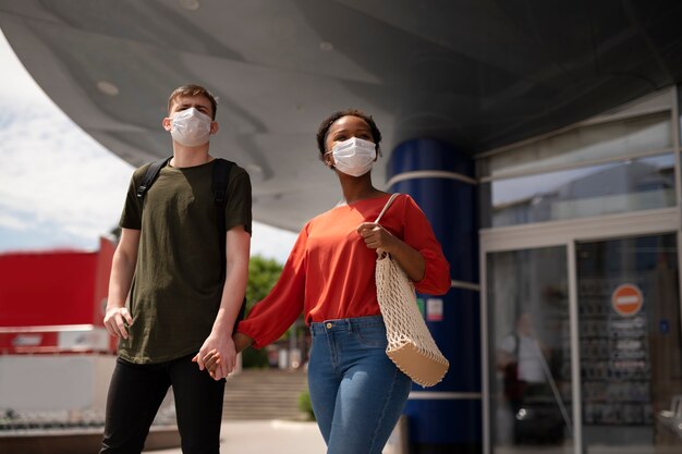 Hombre y mujer tomados de la mano afuera del supermercado mientras usan máscaras médicas