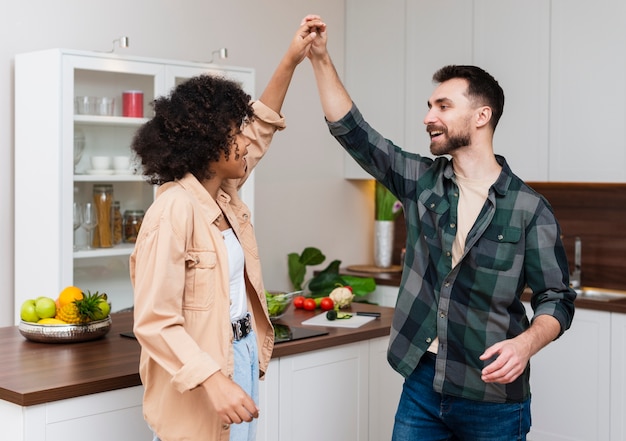 Hombre y mujer tomados de la mano en la cocina