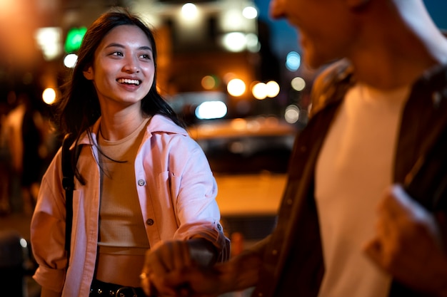 Hombre y mujer tomados de la mano por la noche en las luces de la ciudad