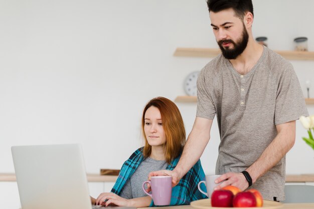 Hombre y mujer tomando café y usando la computadora portátil