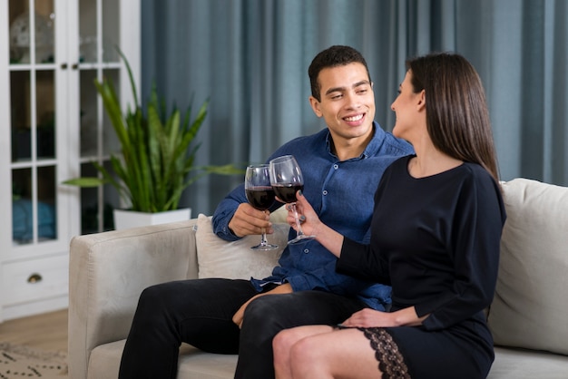 Hombre y mujer tomando una copa de vino mientras está sentado en el sofá