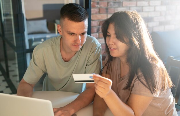 Hombre y mujer usando laptop para compras en línea con tarjeta de crédito