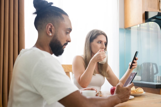 Hombre y mujer usando su teléfono en la cocina