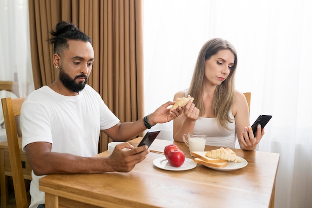 Hombre y mujer usando su teléfono en la cocina