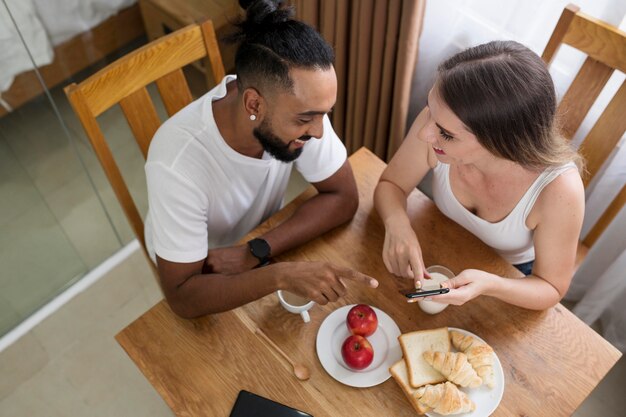 Hombre y mujer usando su teléfono en la cocina