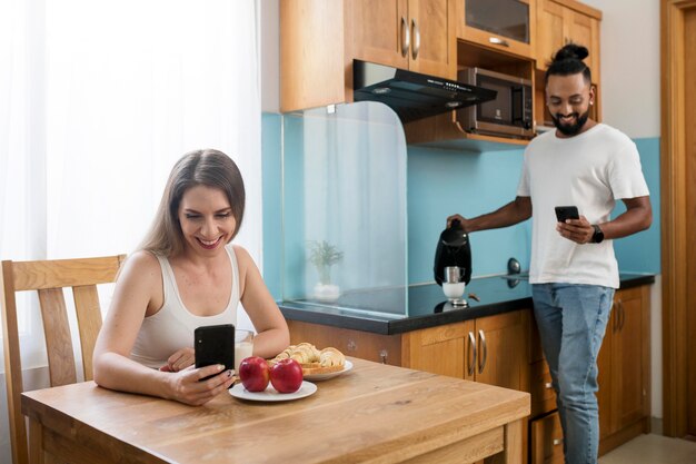 Hombre y mujer usando su teléfono en la cocina