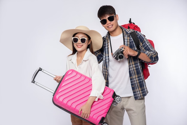 Hombre y mujer vestidos con gafas para viajar con maletas