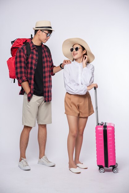 Hombre y mujer vestidos con gafas para viajar con maletas