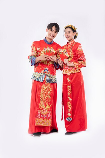 El hombre y la mujer visten Cheongsam y preparan el dinero de regalo rojo para su familia en el día tradicional.