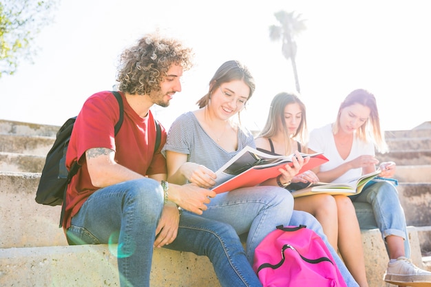 Hombre y mujeres leyendo libros de texto en un día soleado