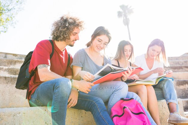 Hombre y mujeres leyendo libros de texto en un día soleado