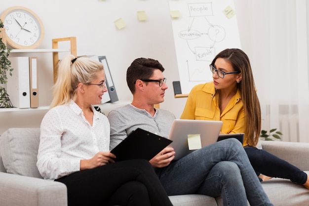 Hombre y mujeres sentados en el sofá y hablando de negocios