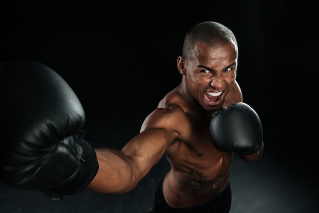 Hombre musculoso afroamericano box fighter practicando patadas