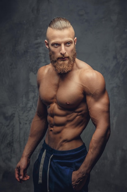 Foto gratuita hombre musculoso con barba mostrando su gran cuerpo sobre fondo gris.