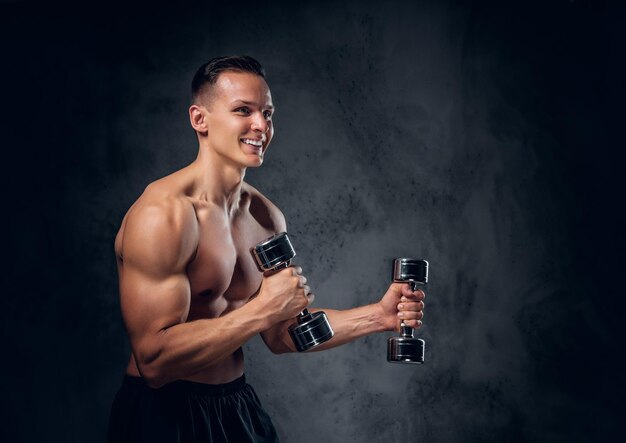 El hombre musculoso sin camisa sostiene un juego de pesas sobre un fondo de viñeta gris oscuro.