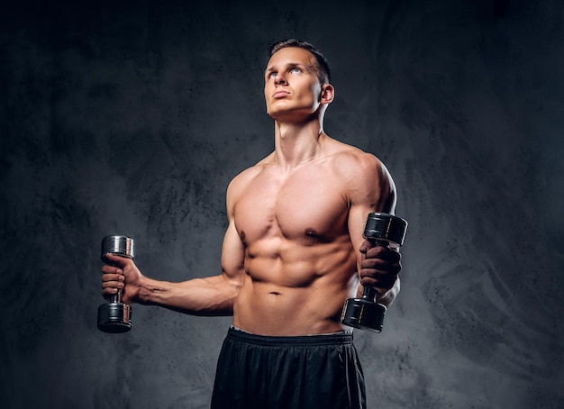 El hombre musculoso sin camisa sostiene un juego de pesas sobre un fondo de viñeta gris oscuro.