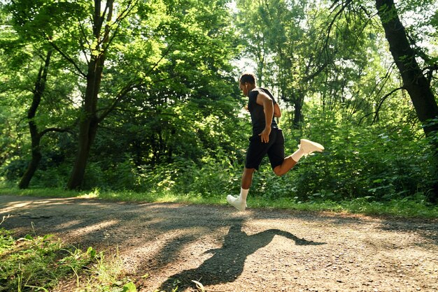 Hombre musculoso corriendo en la pasarela del parque