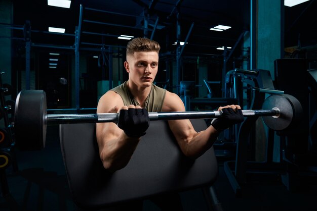 Hombre musculoso entrenando bíceps con barra