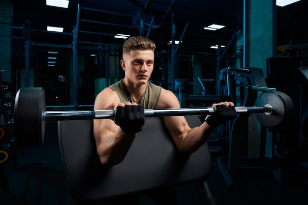 Hombre musculoso entrenando bíceps con barra