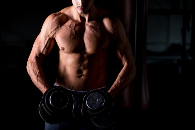 Hombre musculoso haciendo ejercicios con pesas en el gimnasio