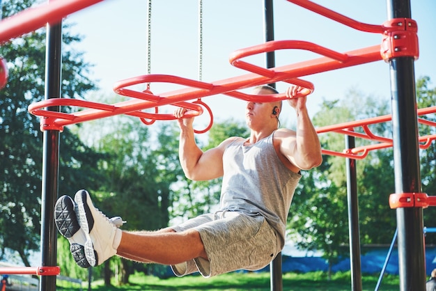 Hombre musculoso con hermoso torso haciendo ejercicio en barras horizontales