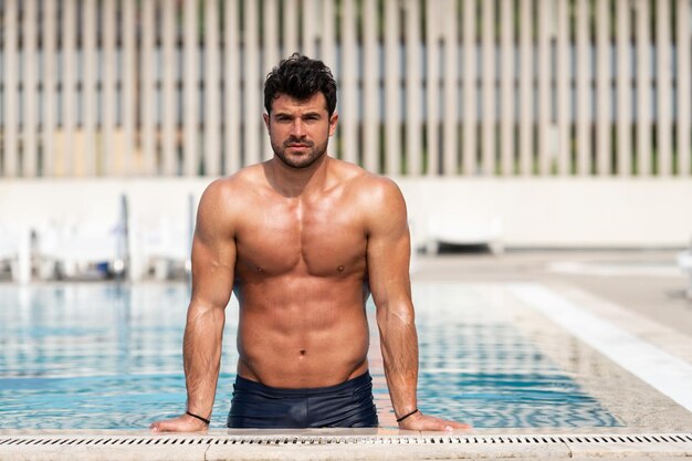 Hombre musculoso joven en la piscina al aire libre