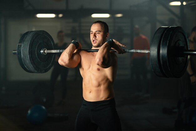 Hombre musculoso levantando pesas en entrenamiento de fuerza en un gimnasio