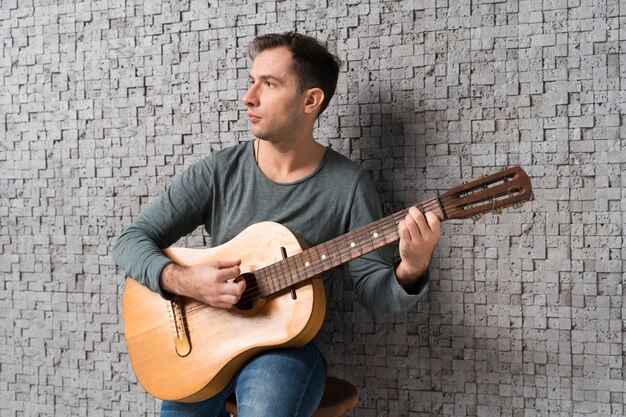 Hombre músico en el interior tocando la guitarra clásica