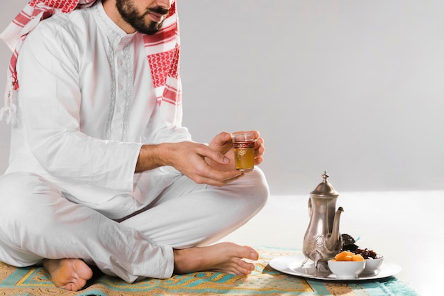 Foto gratuita hombre musulmán que sostiene una pequeña taza de té tradicional