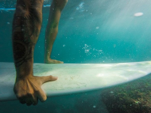 Hombre nadando en tabla de surf bajo el agua