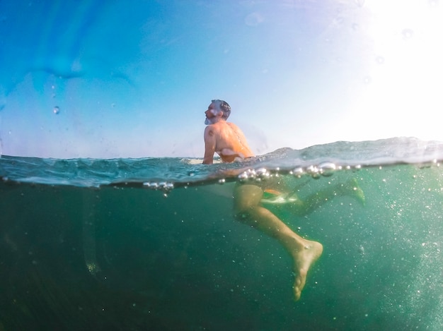 Hombre nadando en la tabla de surf en el mar