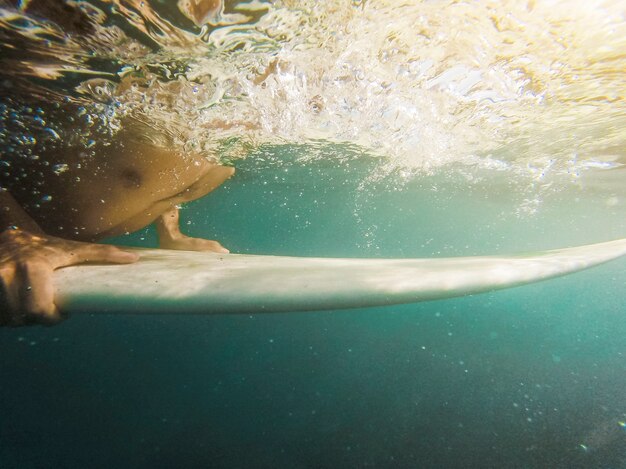 Hombre nadando en la tabla de surf en el océano