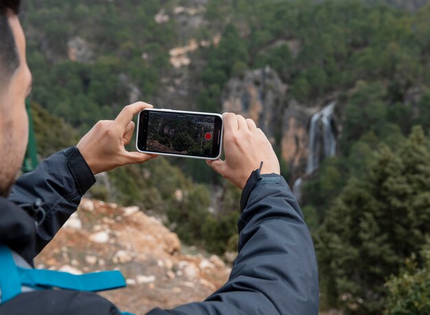 Hombre en la naturaleza tomando fotos con el móvil