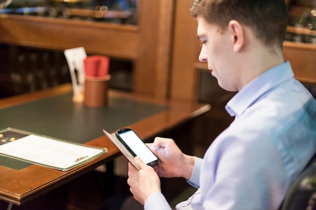 Hombre navegación por teléfono inteligente en el restaurante