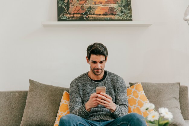 Hombre navegación por teléfono inteligente en la sala de estar