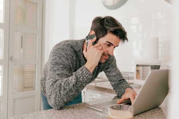 Hombre navegando portátil y hablando por teléfono