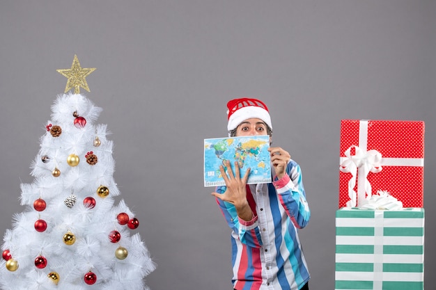 Hombre de Navidad de vista frontal con gorro de santa de resorte espiral que muestra el mapa del mundo