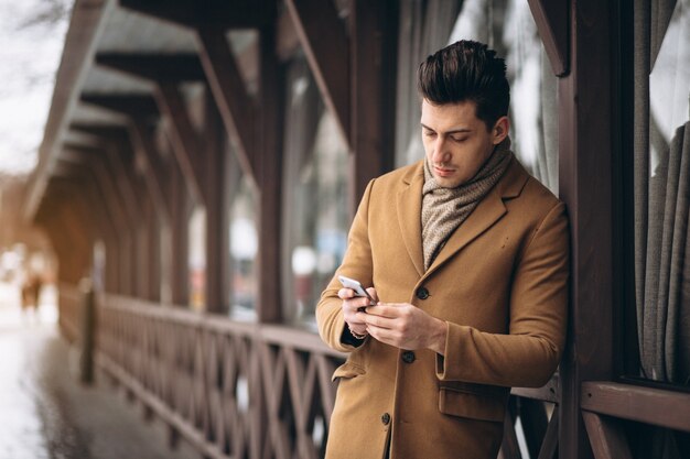 Hombre de negocios en abrigo hablando por teléfono afuera