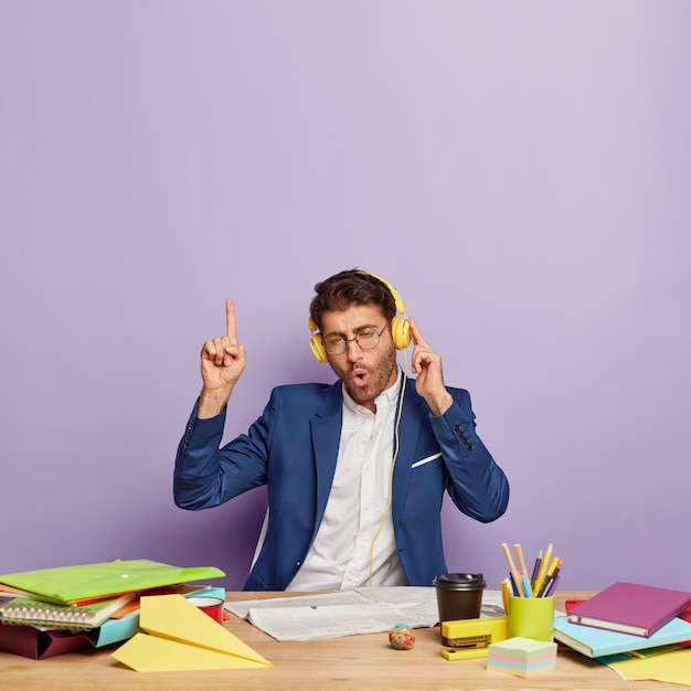 Hombre de negocios acertado alegre divertido que se sienta en el escritorio de oficina