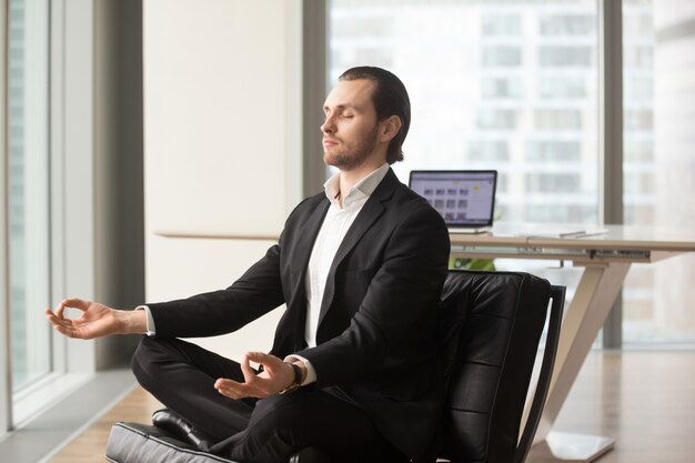 Hombre de negocios acertado que medita en el lugar de trabajo