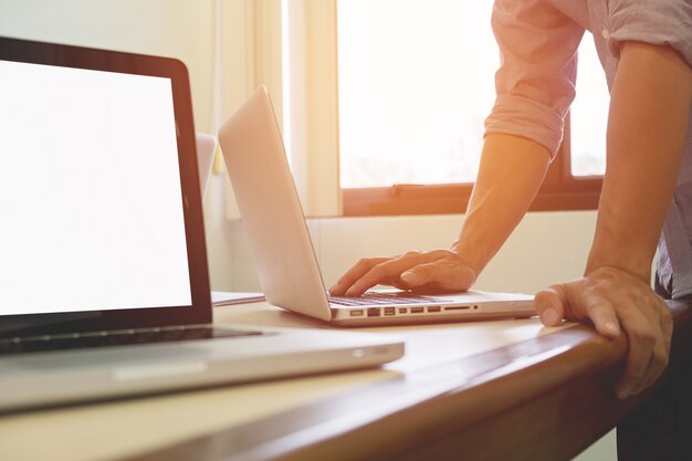 Hombre de negocios adulto joven que mecanografía usando la computadora portátil en oficina