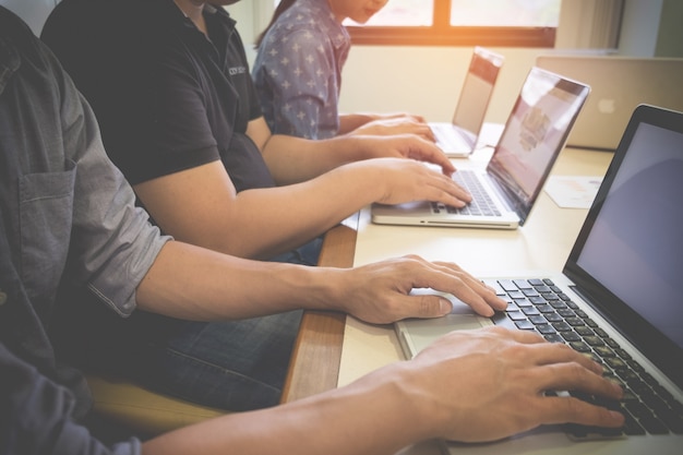 Hombre de negocios adulto joven que mecanografía usando la computadora portátil en oficina